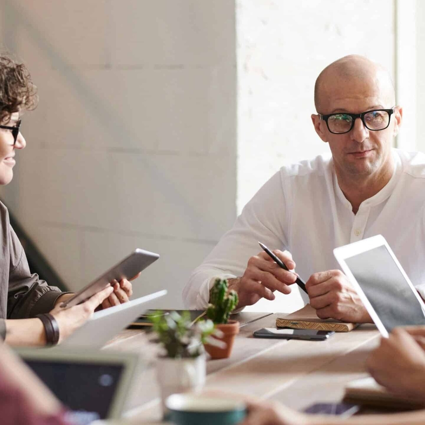 headful software Four people sit around a table in an office meeting, using tablets and notebooks to boost collaboration and productivity as they engage in discussion.
