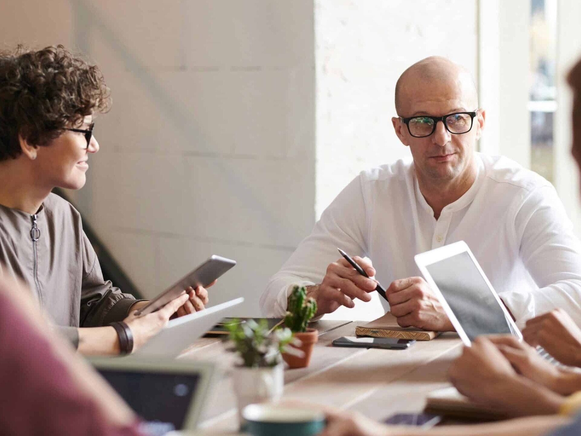 headful software Four people sit around a table in an office meeting, using tablets and notebooks to boost collaboration and productivity as they engage in discussion.